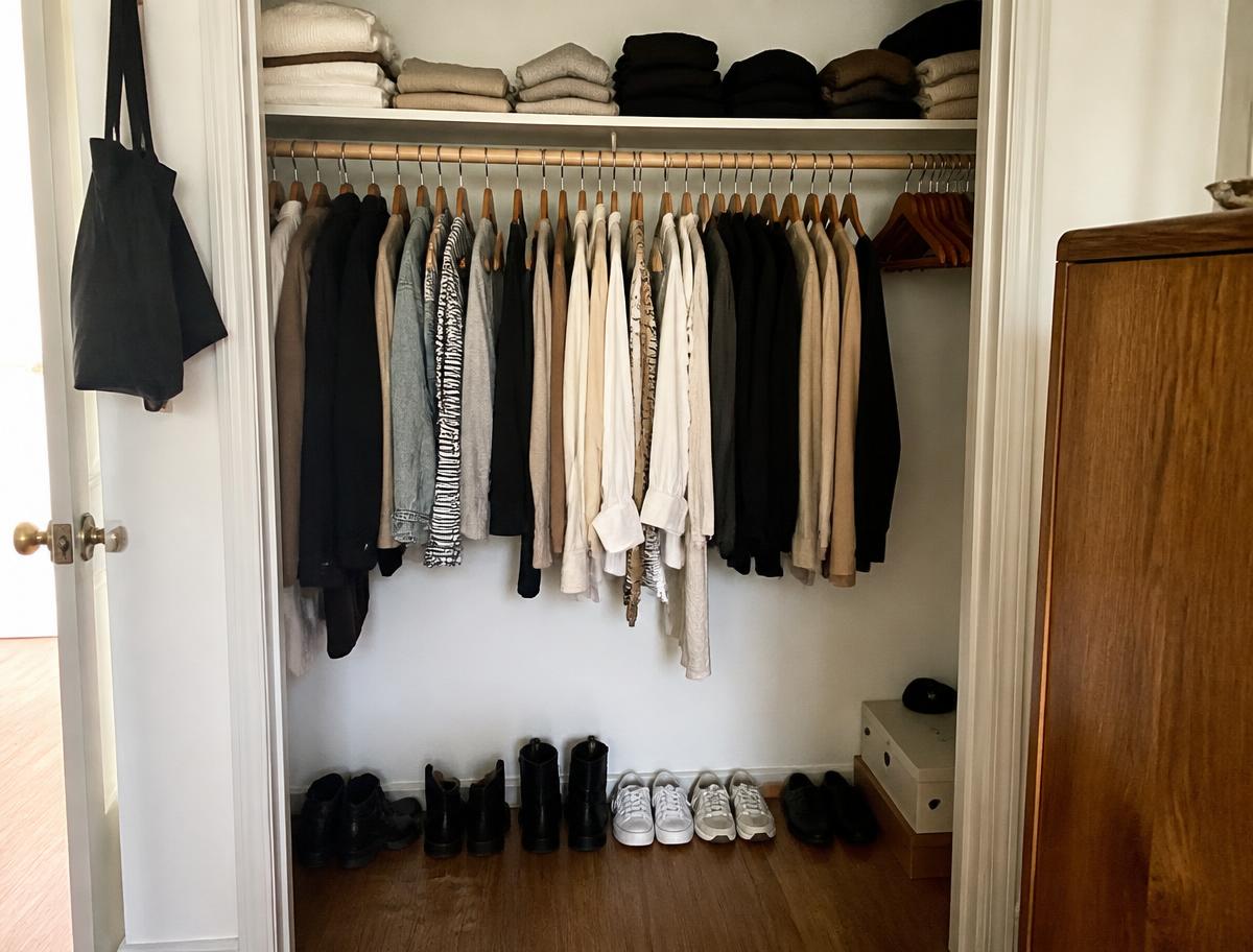 A minimalist clothing rack with neutral and burgundy garments.
